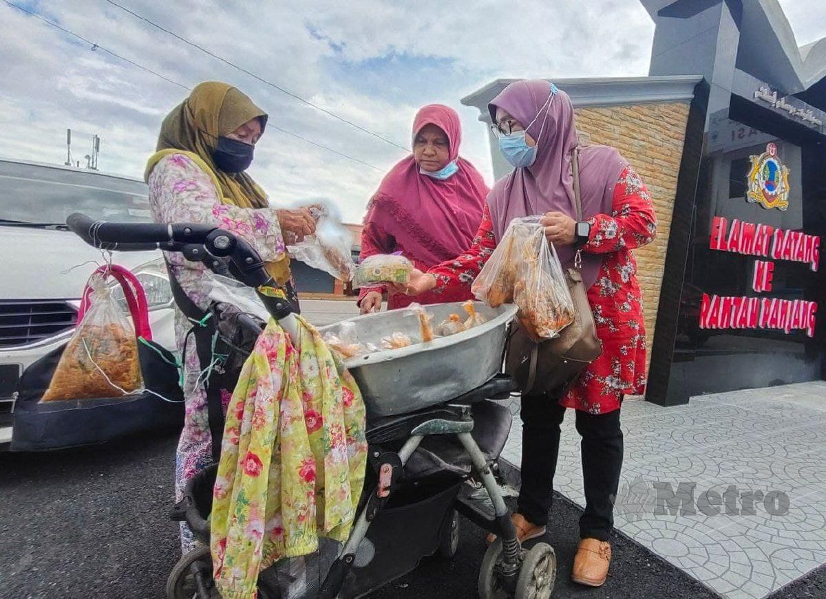 Fisah (kiri) melayan pelanggan yang membeli ayam percik yang dijualnya ketika ditemui di pekan Rantau Panjang. FOTO SYAHERAH MUSTAFA