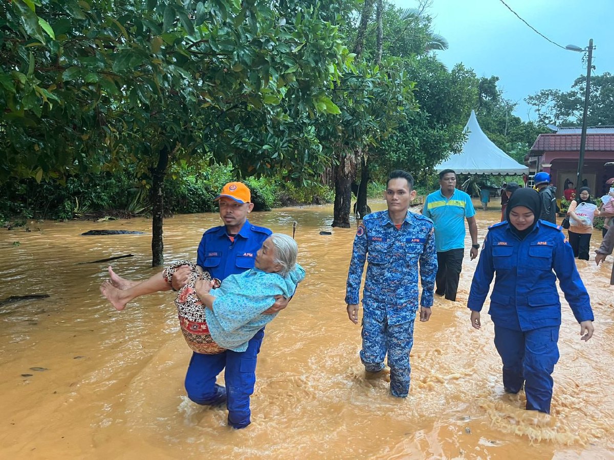 ANGGOTA APM mengangkat wanita warga emas selepas kawasan rumahnya di Kampung Gapam, Jasin dilanda banjir kilat. FOTO Ihsan APM Melaka.