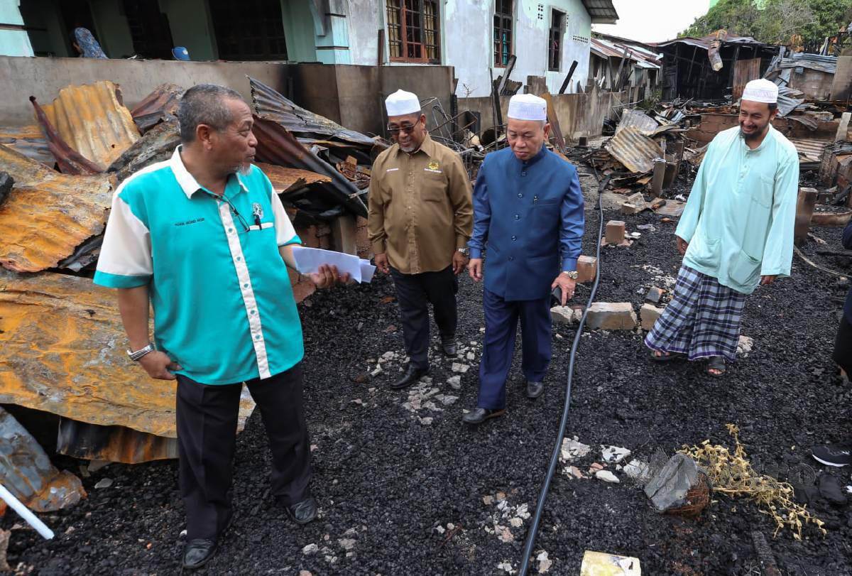 Azami (dua dari kanan) diiringi oleh Setiausaha Agong Pondok Pasir Tumboh, Ahmad Shairazi Atiqullah (kanan) melawat keadaan kawasan rumah yang hangus membabitkan 10 buah rumah sewa dalam kebakaran di Kampung Terusan Limbat. FOTO NIK ABDULLAH NIK OMAR