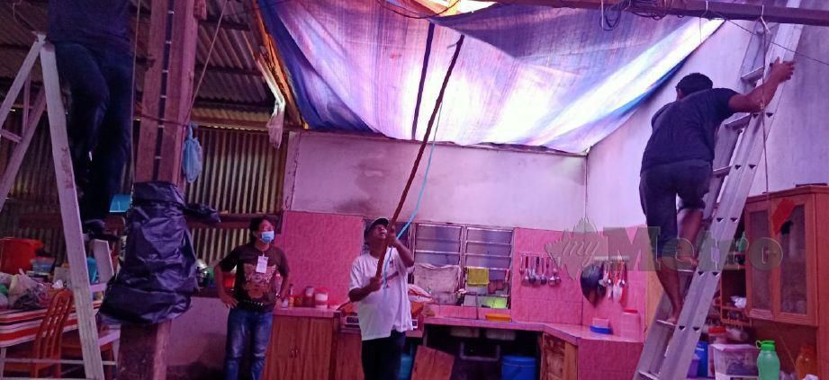 ABDUL Azeez membantu memasang bumbung dengan plastik untuk sementara di rumah Halimah Hamad, di Kampung Sera Ulu, Pulai. FOTO SAFURI KAMARUDIN.