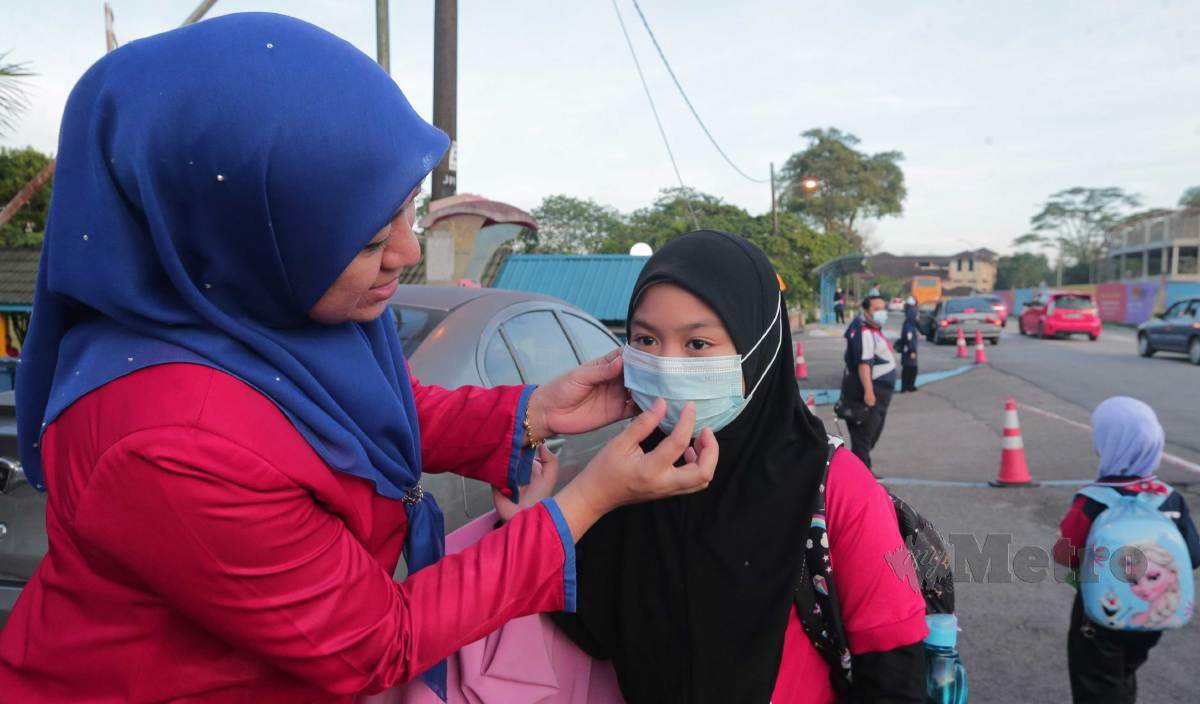 AZIZAH membetulkan pelitup muka anaknya ketika menghantar ke Sekolah Kebangsaan Taman Molek, Johor Bahru.  FOTO Nur Aisyah Mazalan