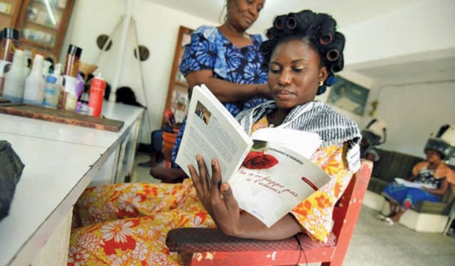 SEORANG wanita memanfaatkan masanya dengan membaca semasa rambutnya didandan.