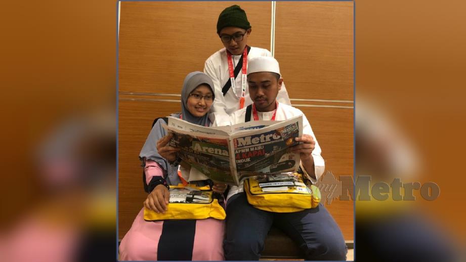 Mohamad Syafiq (duduk kanan) bersama Nur Amalina dan Mohamad Asyraf membaca Harian Metro sebelum berlepas ke Tanah Suci. FOTO Mohamad Hussin 