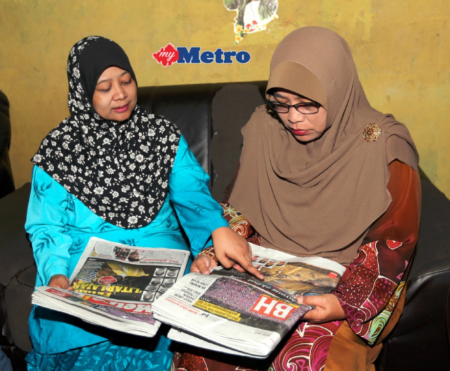 Asiah (kanan) bersama ibu kepada Allahyarham Mohammad Azrie Zulkefli, Fatimah Nasir membaca akhbar mengenai kejadian yang menimpa anaknya di Taman Sinaran Kempas. FOTO Zulkarnain Ahmad Tajuddin