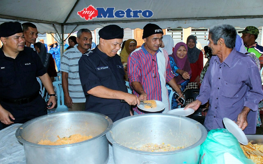 Ketua Polis Kelantan, Datuk Dr Ab Rahman Ismail (dua kiri) membantu menghidangkan makanan kepada mangsa banjir di PPS SMK Pak Badol, Bachok. FOTO Nik Abdullah Nik Omar 