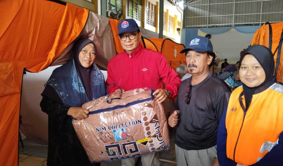SITI Badariah (kiri) menerima selimut dari Samsolbari di PPS SK Kota Dalam Ayer Hitam.