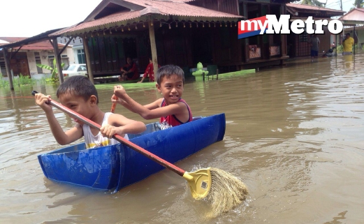 MUHAMMAD Reza Hakimi Rizam, 8, (belakang) bersama adiknya, Muhammad Ramadani, 6, menggunakan tong sebagai sampan ketika banjir melanda selepas hujan lebat bermula jam 5 pagi di Kampung Pulau Kelapa, Batu Hampar, Melaka. FOTO Muhammad Hatim Ab Manan