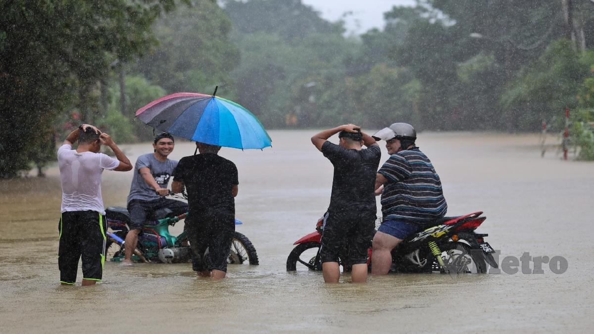 PENUNGGANG motosikal meredah banjir di Kampung Kepah. FOTO GHAZALI KORI