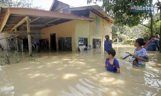 SEBUAH keluarga menyelamatkan diri ke kawasan lebih tinggi dalam kejadian banjir kilat di Kampung Simpang Tiga, Kepala Batas. FOTO Danial Noordin