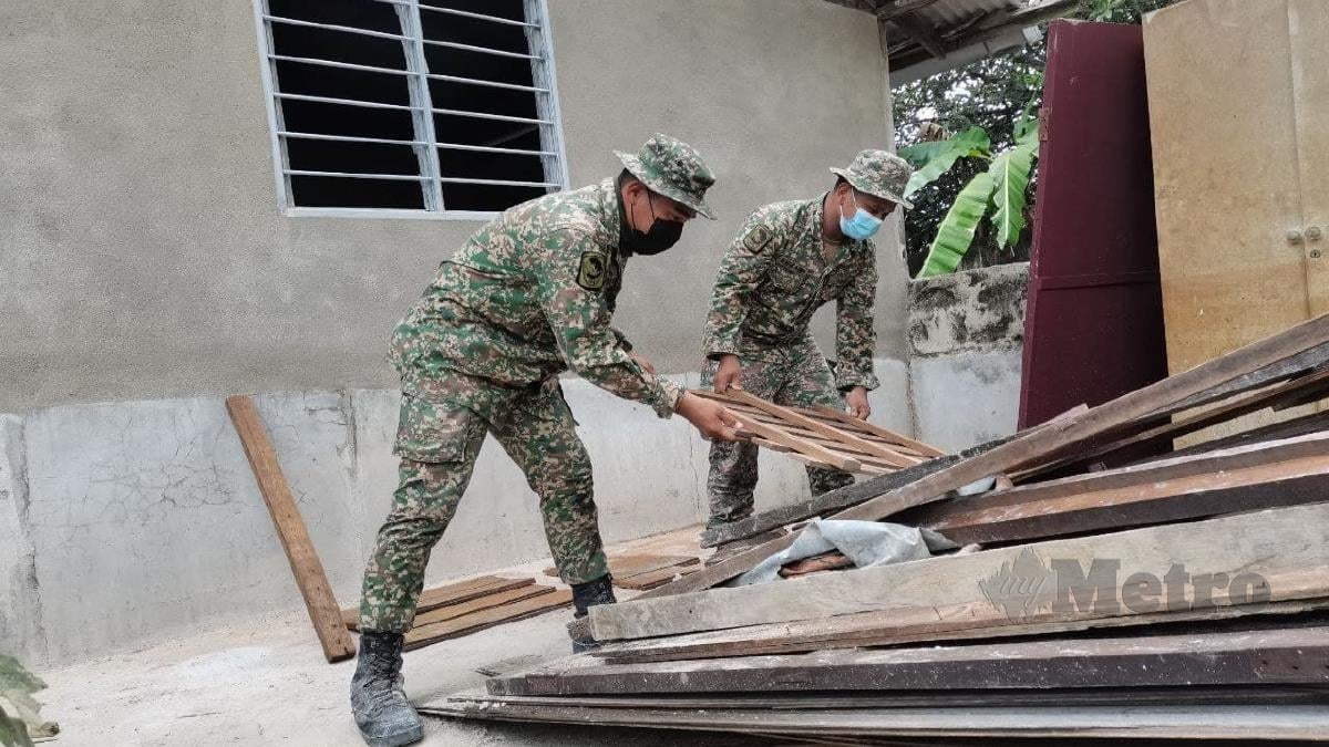 ANGGOTA Angkatan Tentera Malaysia (ATM) melakukan tugas membaik pulih rumah Fatimah. FOTO Ahmad Hasbi 