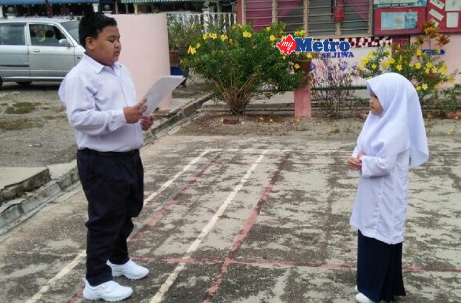 Nor Syarwani Ahmad Kamal membaca ikrar dengan murid tahun satu Dhia Sofea Mohd Ridzuan ketika sesi persekolahan 2017 SK Tebing Rebak, Bagan Datoh bermula hari ini. - Foto  ABU BAKAR AL SIDEK)