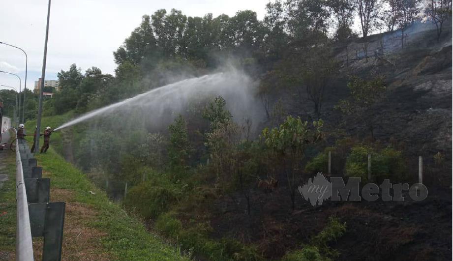 ANGGOTA bomba berusaha memadam kebakaran hutan berhampiran susur keluar ke Nilai arah utara, hari ini. FOTO ihsan bomba.