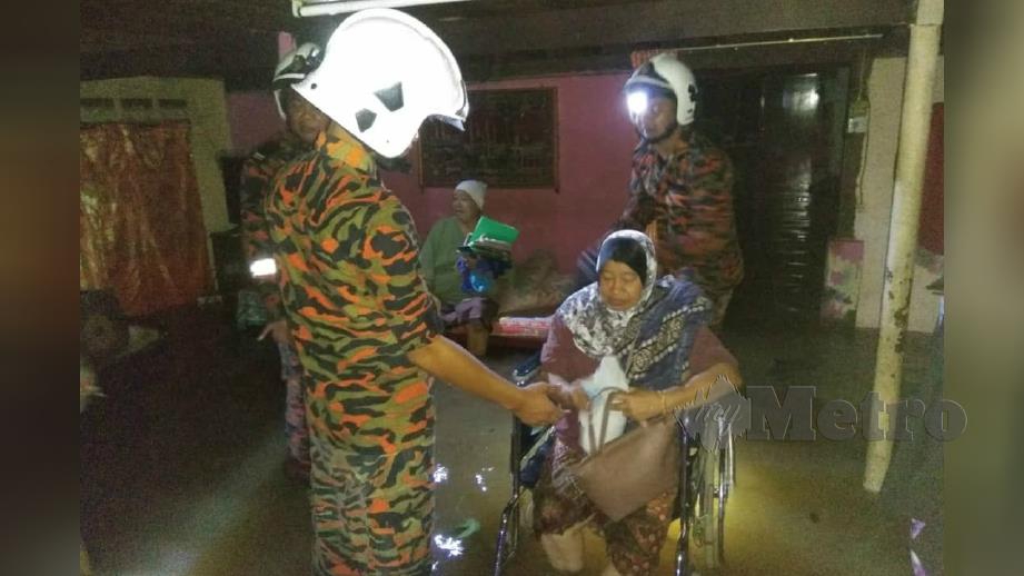 Anggota bomba membantu warga emas untuk dipindahkan selepas rumah mereka di Batu 10, Jalan Sungai Petani-Alor Setar di Kota Sarang Semut di sini, dilanda banjir kilat malam tadi. Foto Ihsan JBPM