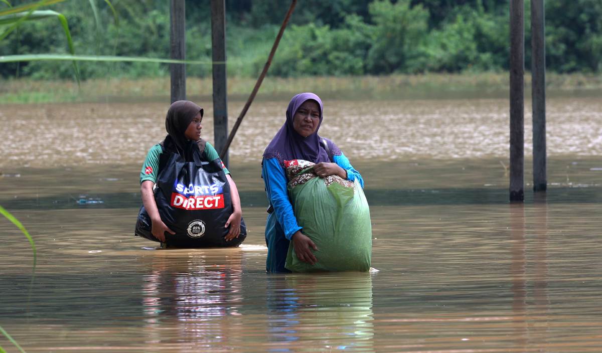 MANGSA banjir di Kampung Bukit Mukim Derang membawa barang keperluan ke Pusat Pemindahan Banjir selepas rumah mereka dinaiki air. FOTO BERNAMA