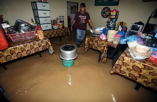 ASMARI Subar melihat barang-barang di kedai makanannya yang ditenggelami air banjir akibat hujan lebat di Kampung Baru, Kilometer 12, Jalan Sintok.
