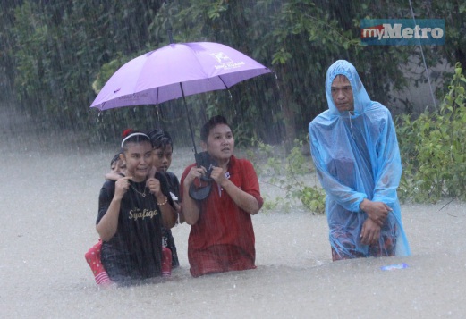 SATU keluarga di Kampung Baroh Pial terpaksa mengharungi banjir untuk ke pusat pemindahan selepas kediaman mereka dinaiki air. FOTO Bernama