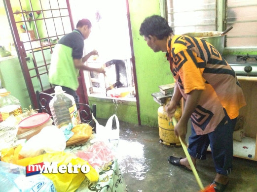 ABDUL Rahman (kanan) bersama anaknya sedang membersihkan rumah mereka yang dinaiki air.