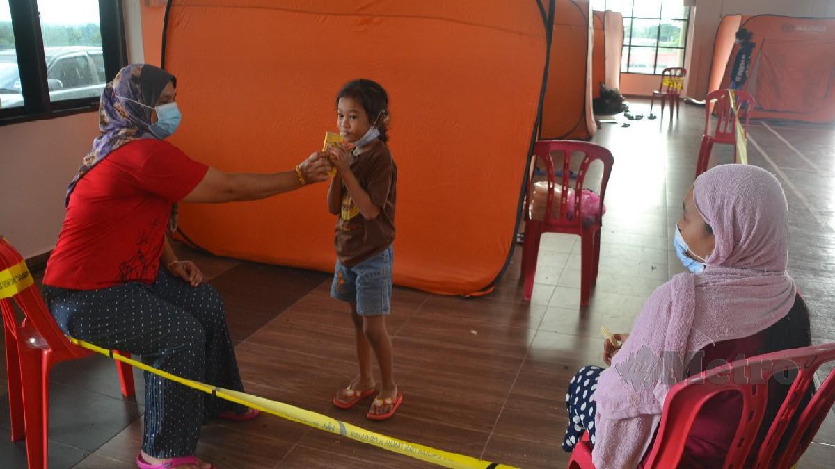 ELFI Rahmi memberi minum kepada Nurhana Umaira Ahmad Faizal sambil diperhatikan ibu Nurhana, Aziah Samsudin di PPS Dewan JAPERUN Durian Tunggal, Alor Gajah, hari ini. FOTO HASSAN OMAR