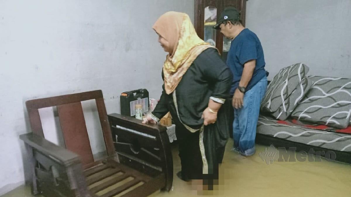 MANGSA banjir di Rumah Awam Ayer Molek, Sawiyah Mansor, 62, mengemas barang di kediamannya yang dinaiki air. FOTO Nuraliawati Sabri.