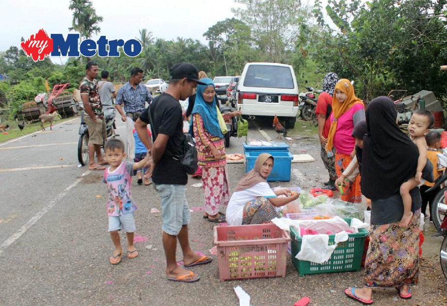 Penduduk Kampung Kubang  Sawa, membeli keperluan harian di tepi jalan berikutan terputus hubungan sejak banjir melanda kampung itu. FOTO Nik Abdullah Nik Omar 