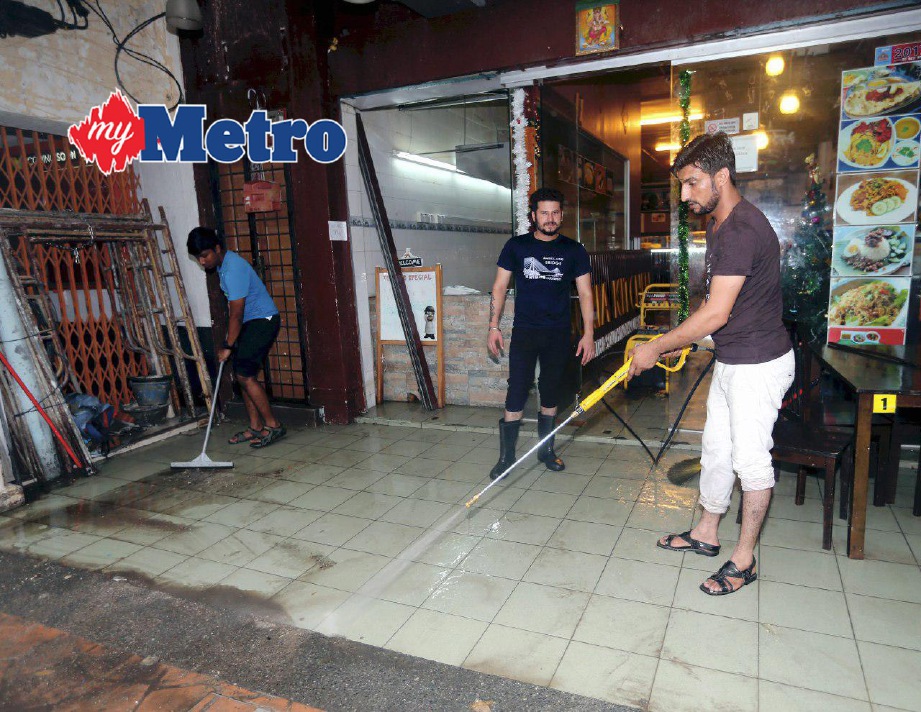 Peniaga mencuci kedai selepas premis mereka dimasuki air akibat banjir kilat di Jalan Segget, Johor Bahru. FOTO Zulkarnain Ahmad Tajuddin. 
