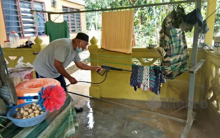 PENDUDUK membersihkan rumahnya yang dilanda banjir di Baling, malam tadi. FOTO SAFURI KAMARUDIN.