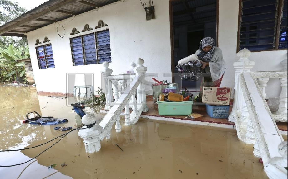 Siti Fatimah Ghani, 42 mengemas peralatan rumah selepas rumahnya dilanda banjir akibat hujan lebat sejak malam tadi di Kampung Tok Lawit, Hulu Terengganu. FOTO Ghazali Kori 