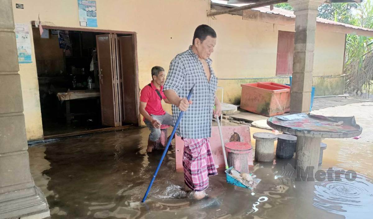 SANI Mamat membuang sampah sarap yang terdapat dalam kedai kopinya di Kampung Bendang Pak Yong hasil bawaan air banjir. FOTO Siti Rohana Idris
