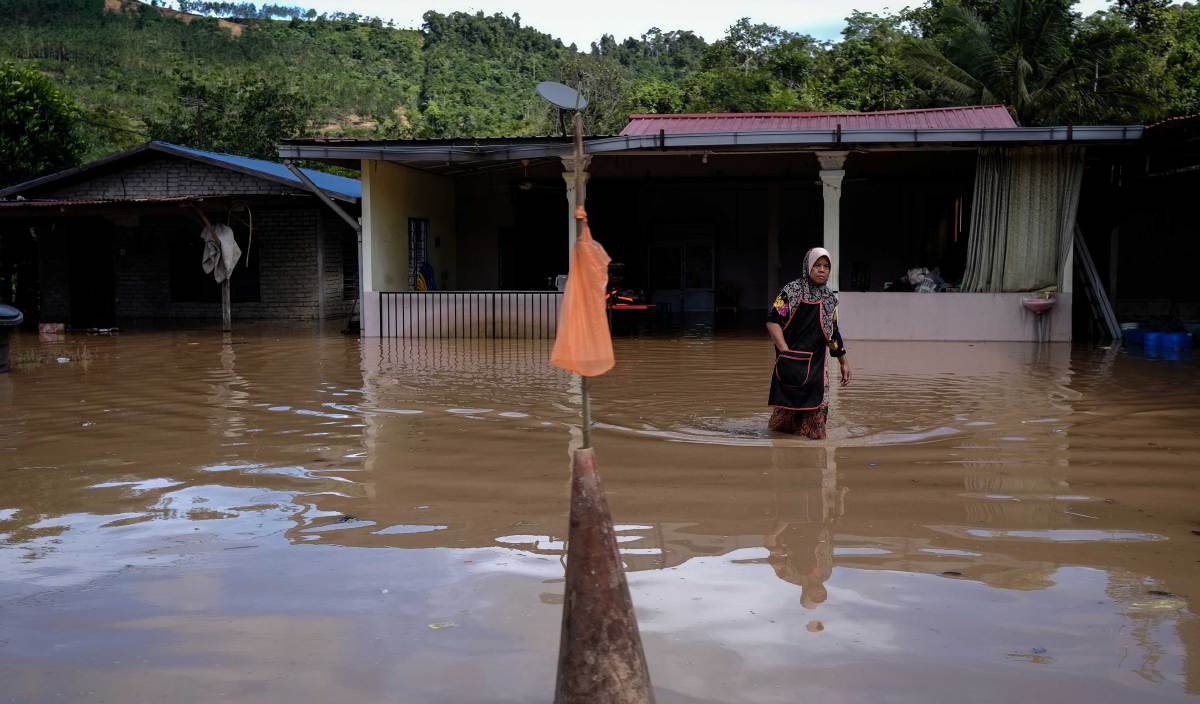 SEORANG wanita dilihat meredah banjir yang melanda rumahnya di sekitar kawasan Paya Garok, Jerantut. FOTO BERNAMA