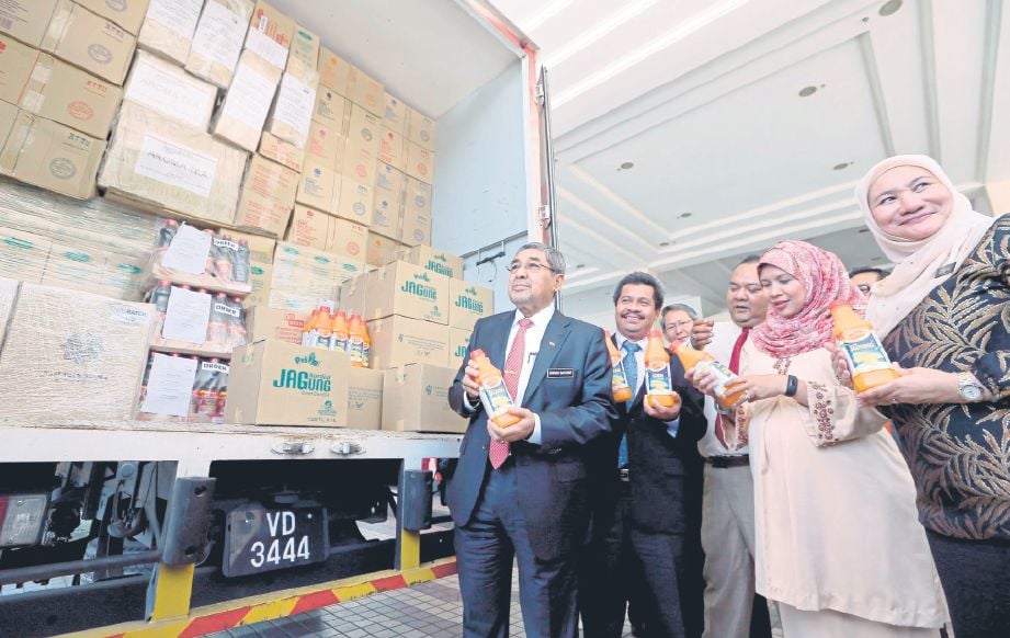 AHMAD Bashah (kiri) bersama Anuar (dua dari kiri) menunjukkan produk minuman pada majlis pelepasan lori yang membawa produk IAT Kedah ke pasaran Singapura.