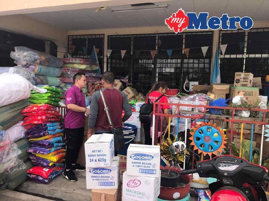 Pengerusi Persatuan Kebajikan Kasih Sayang Aixin Malaysia Datuk Fam Chee Way (kiri) bersama barangan yang disumbangkan kepada mangsa banjir. 