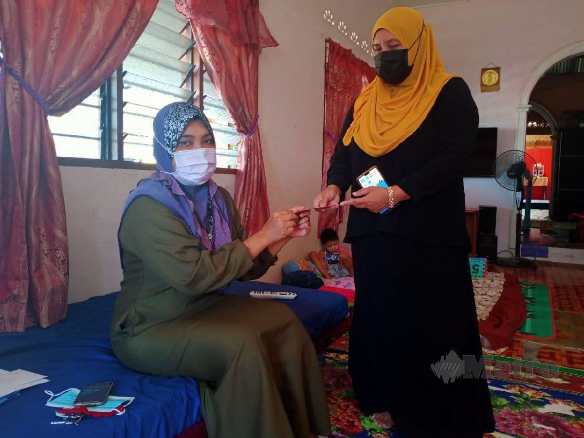 NORFADILAH (kanan) menyampaikan sumbangan berupa wang tunai kepada Noor Arlina yang menghidap penyakit Crohn’s sejak 2019 ketika ditemui di rumahnya di Felda Lui Selatan 1, Bahau. FOTO MOHD KHIDIR ZAKARIA.
