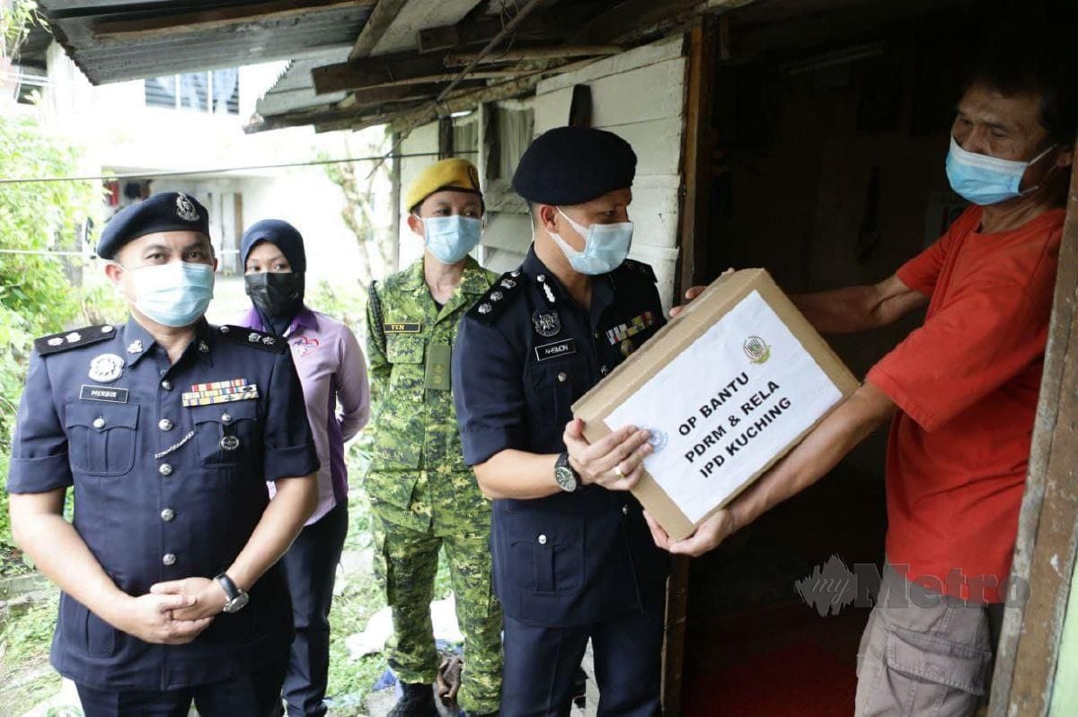 Asmond mengagihkan bakul bantuan makanan kepada 6, buah keluarga sempena OP Bantu - IPD Kuching bersama pihak Rela. FOTO NADIM BOKHARI