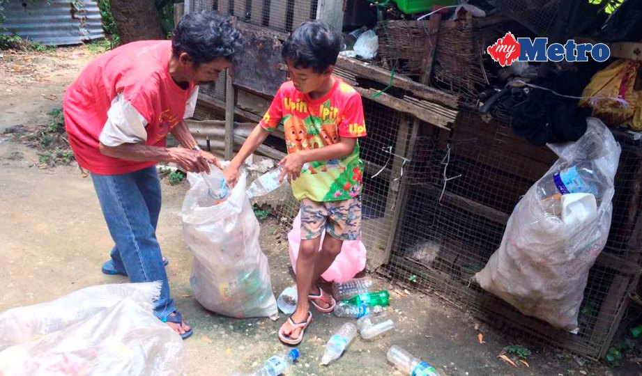 SUKRI bersama anak bongsunya memasukkan botol plastik ke dalam guni untuk dijual. FOTO Hazira Ahmad Zaidi 