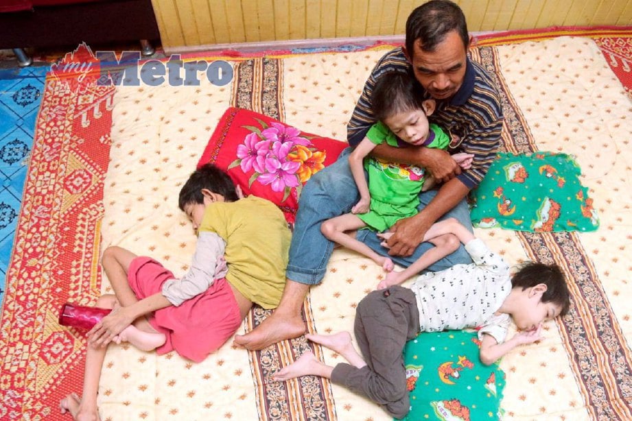Mohd Zain menjaga dan merawat tiga anaknya yang menghidap CP ketika ditemui di rumahnya di Kampung Kok Keli 1, Tumpat. FOTO FARIS ZAINULDIN