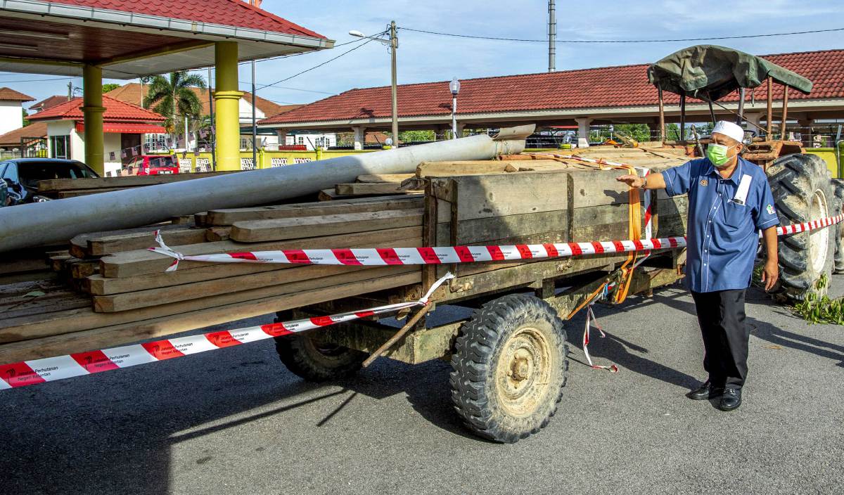 ABDUL Khalim memeriksa sejumlah kayu pelbagai jenis yang berjaya disita dalam operasi bersepadu khazanah siri 18, di Pejabat Hutan Jajahan Kelantan Timur. FOTO BERNAMA