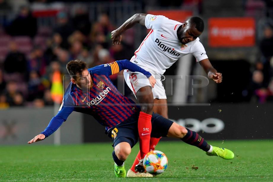 PENYERANG Barcelona, Lionel Messi (kiri) diasak pertahanan Sevilla dari Perancis, Ibrahim Amadou pada suku akhir kedua Piala Raja Sepanyol di Nou Camp, Rabu lalu. - FOTO AFP