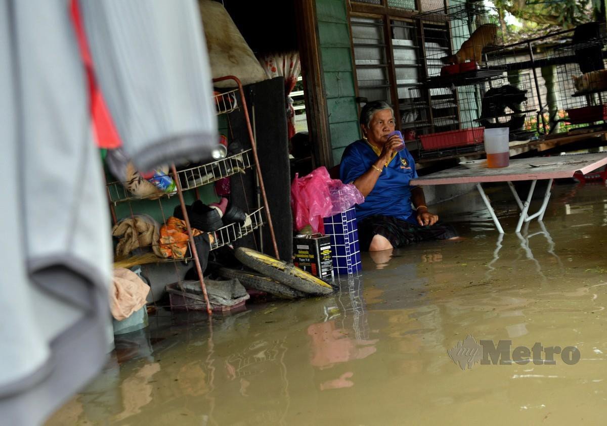 PENDUDUK setempat menikmati minuman selepas melakukan kerja mengalihkan barangan di rumahnya yang terjejas akibat banjir di Kampung Changkat Jong. FOTO BERNAMA