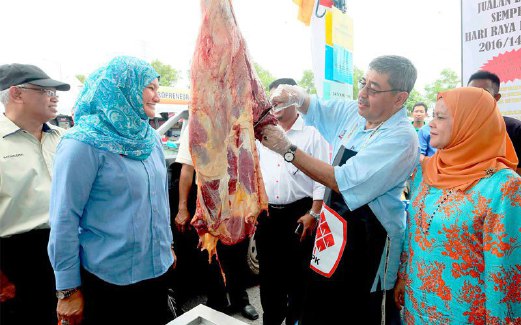 AHMAD Bashah memotong daging lembu sambil perhatikan isterinya, Datin Seri Hizam Awang Ahmad (kiri).