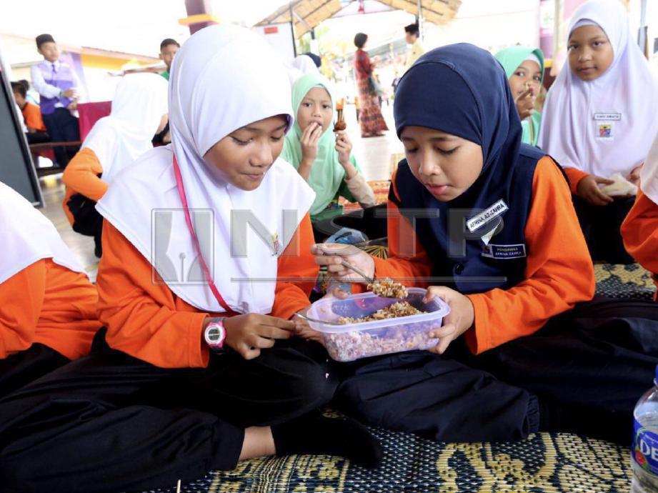 Afrina Az-Zahra (kanan) berkongsi bekal makanan dengan kawan baiknya, Syazafilza  di kantin SK Kampung Tun Razak, Bukit Katil.  FOTO Khairunisah Lokman