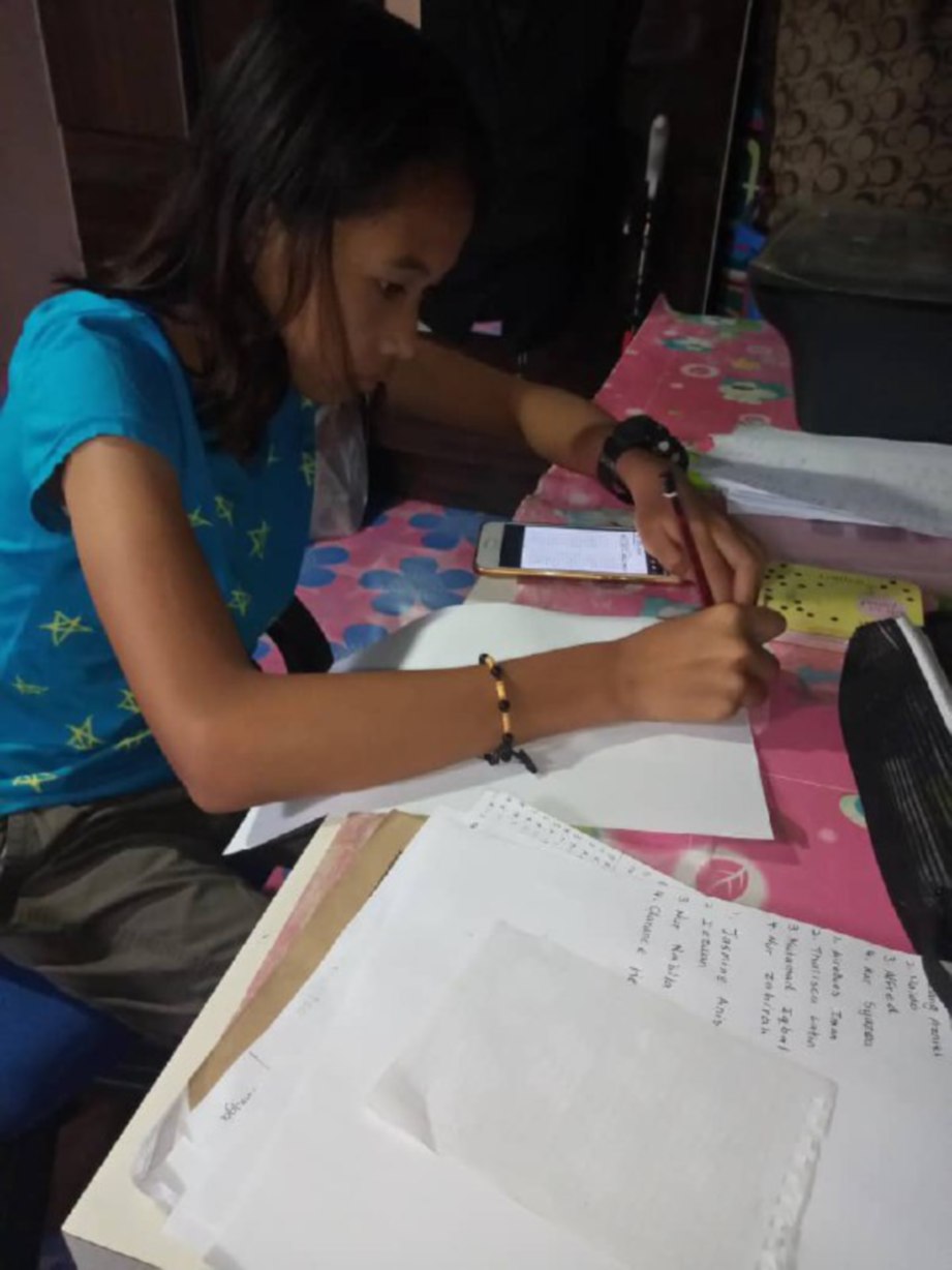 NUR Nabila Natasha Yazid, 12, membuat kerja sekolah yang diberikan gurunya melalui aplikasi secara dalam talian sepanjang tempoh PKP.