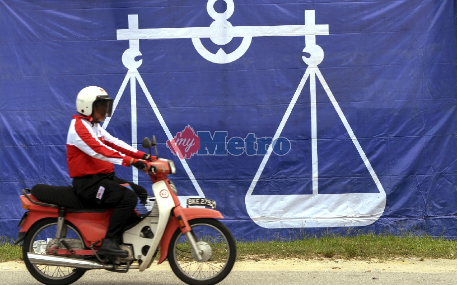 Posmen melintasi bendera BN yang menghiasi sekitar Pusat Daerah Mengundi (PDM) Kota Selatan di Kota Bharu. FOTO BERNAMA