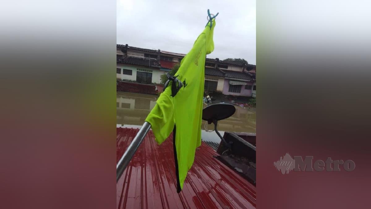Muhammad Razlan memasang baju di bumbung rumahnya untuk dijadikan bendera bagi menarik perhatian pihak berkuasa selepas terperangkap lebih 24 jam. FOTO ihsan pembaca