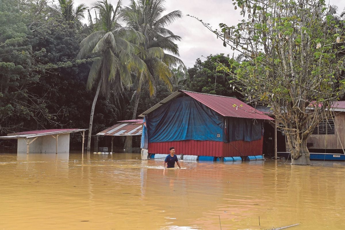 PENDUDUK mengharungi air banjir di Kampung Paya Panjang, Bera, semalam. FOTO BERNAMA 