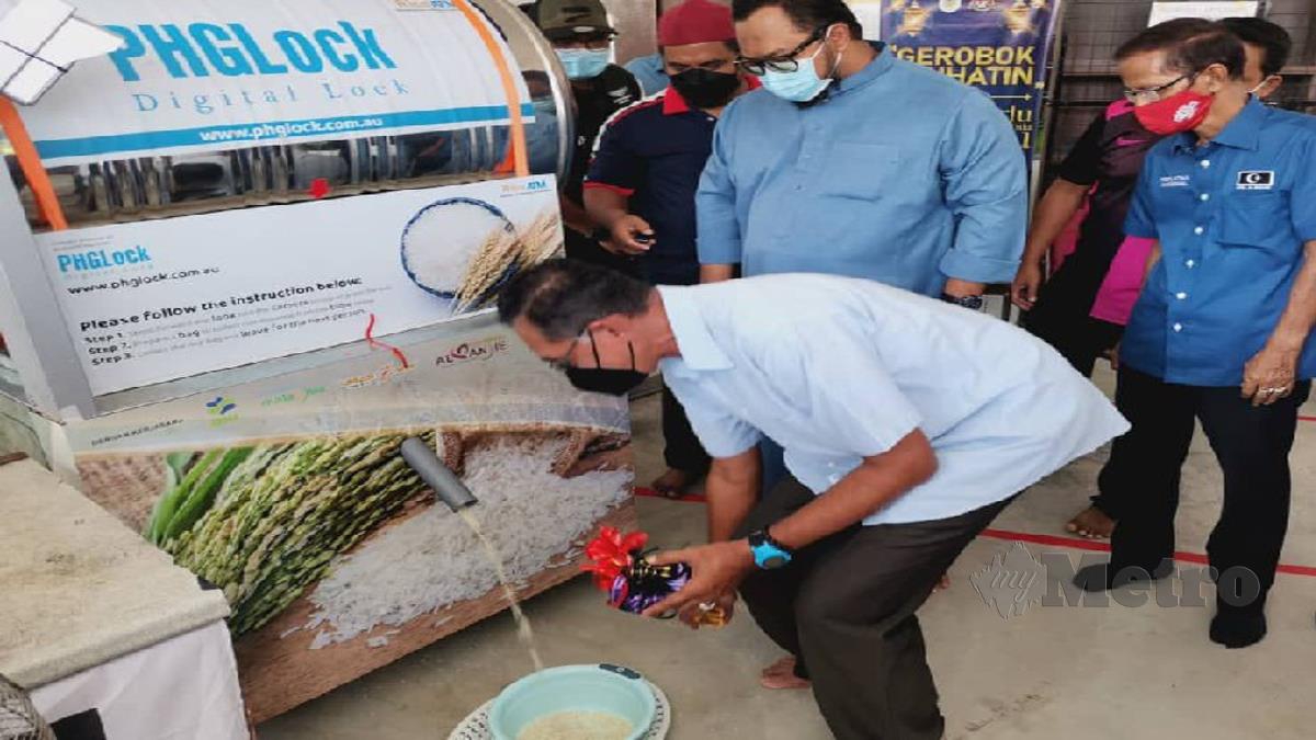 DATUK Rosol Wahid melihat proses pengeluaran beras daripada Mesin ATM Beras yang diberikan secara percuma kepada golongan memerlukan. FOTO ZAID SALIM