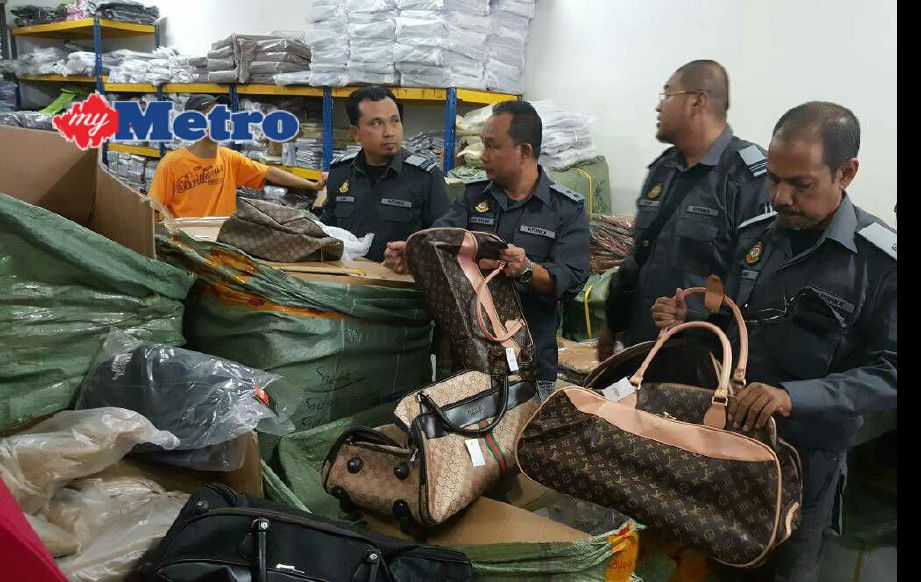 Penguat kuasa KPDNKK memeriksa beg berjenama tiruan yang dirampas dalam serbuan di stor simpanan di Rawang. FOTO Amrullah Abdul Karim 