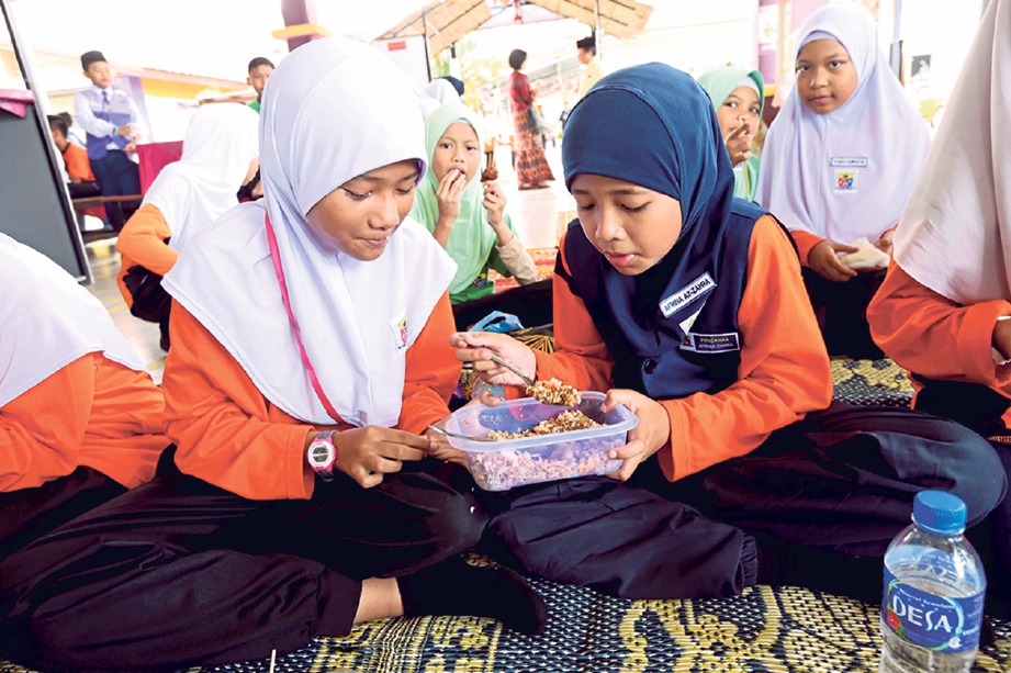 AFRINA Az-Zahra Kamarul Arifin, 10, (kanan) berkongsi bekal makanan dengan kawan baiknya, Syazafilza Shaharudin, 10, (kiri) di kantin Sekolah Kebangsaan Kampung Tun Razak, Bukit Katil. FOTO Khairunisah Lokman