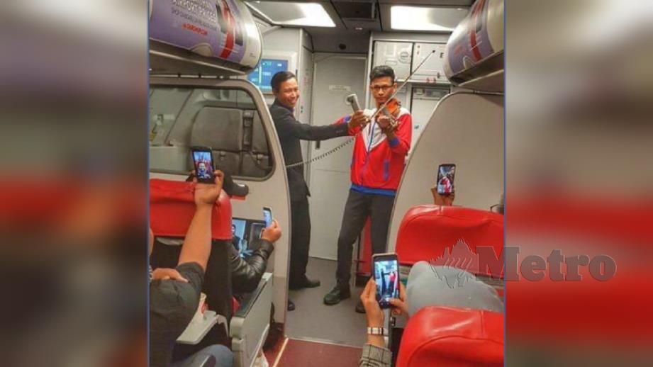 Naqib Naimullah bermain biola di dalam pesawat ketika dalam perjalanan ke Jakarta. FOTO Ihsan Naqib Naimullah Zairul Nizam 