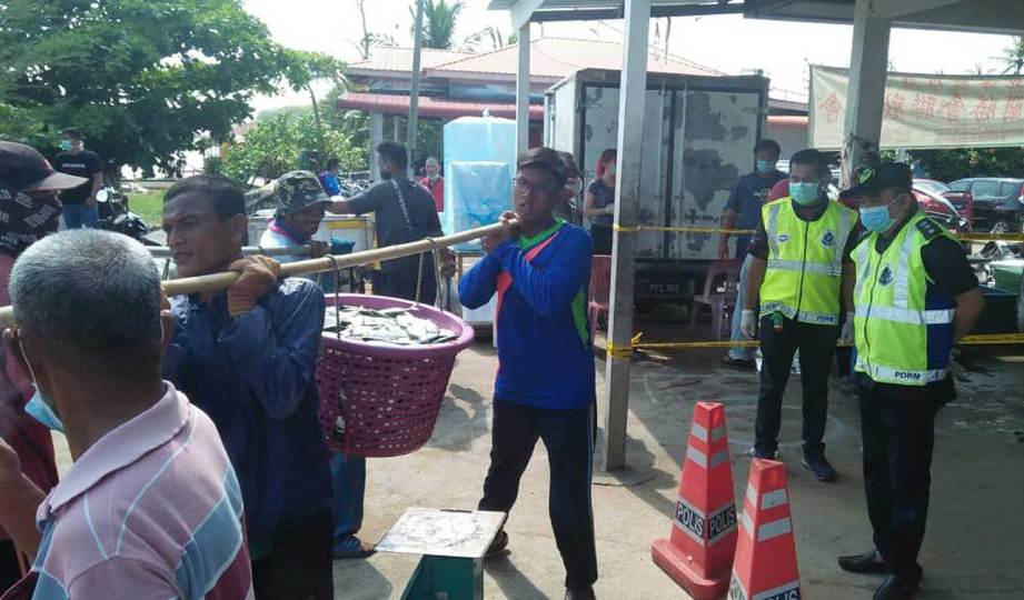 PIHAK berkuasa ketika melakukan persiapan bagi menghentikan aktiviti membeli hasil laut di Pasar Bisik Kuala Muda, Penaga. FOTO Ihsan PDRM