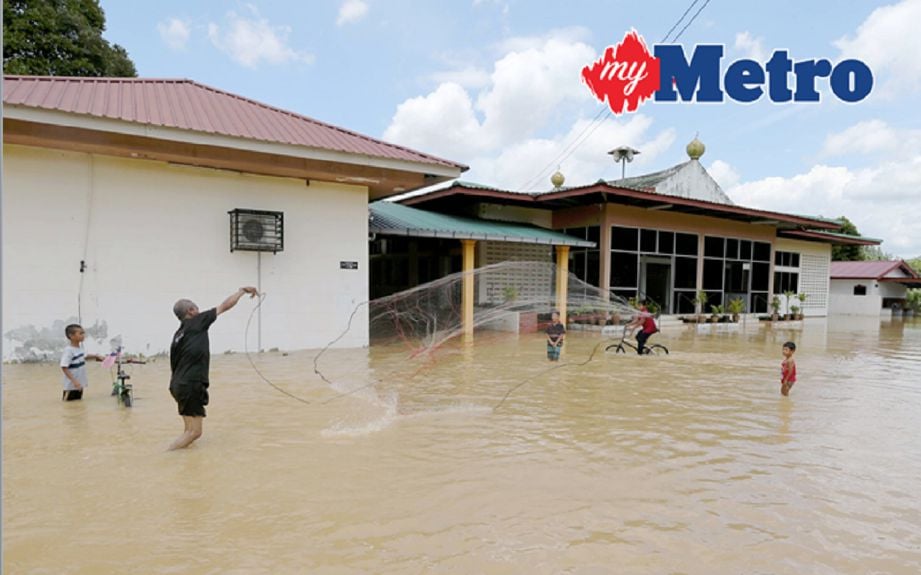 Penduduk sekitar menjala ikan di pekarangan masjid Jamek Raudhatus Solihin yang dinaiki air akibat banjir di Derang dekat Bukit Pinang, Pokok Sena. FOTO SHAHRIZAL MD NOOR